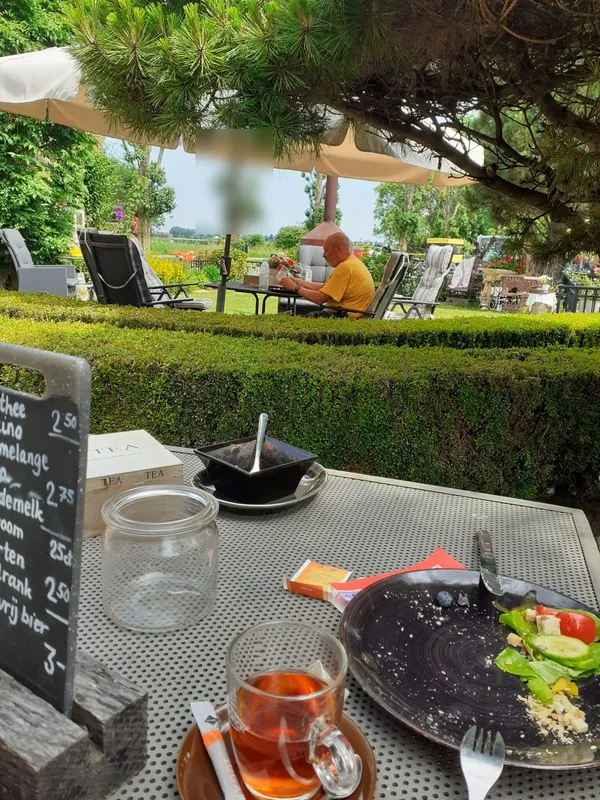 Thee en een broodje aan een tafel in de tuin, met het krijtbord ernaast